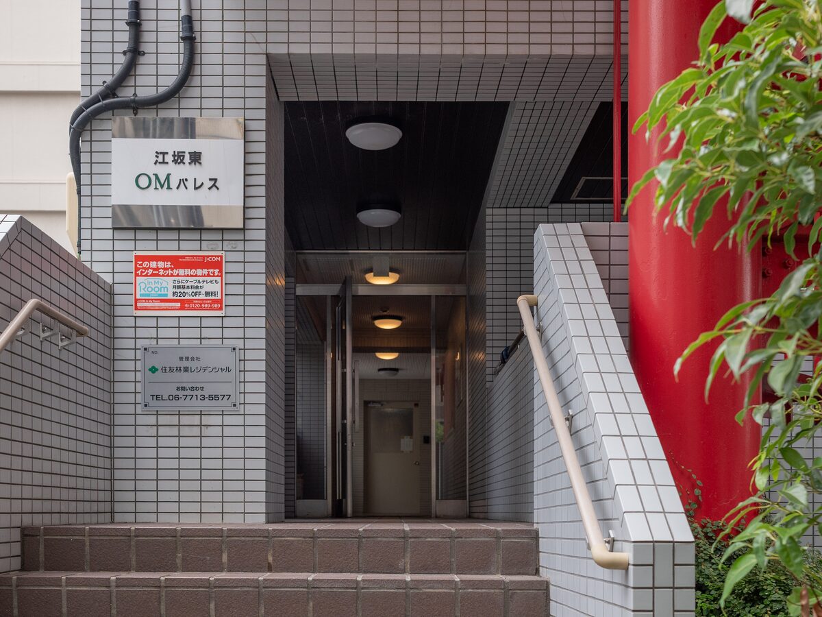 江坂東OMパレスの入口。左手の壁に建物名の銘板があり、数段の階段を上がって中へ入る