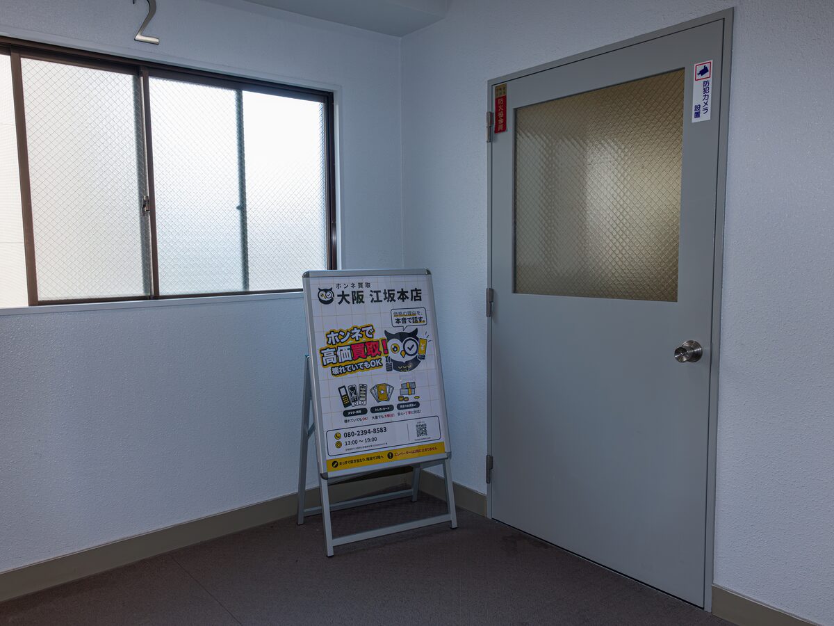 2階の店舗入口。扉の横に「ホンネ買取 大阪 江坂本店」の立て看板